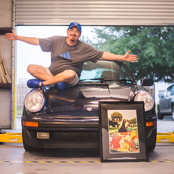 Jason Breitfeller sitting on a porsche with arms wide open